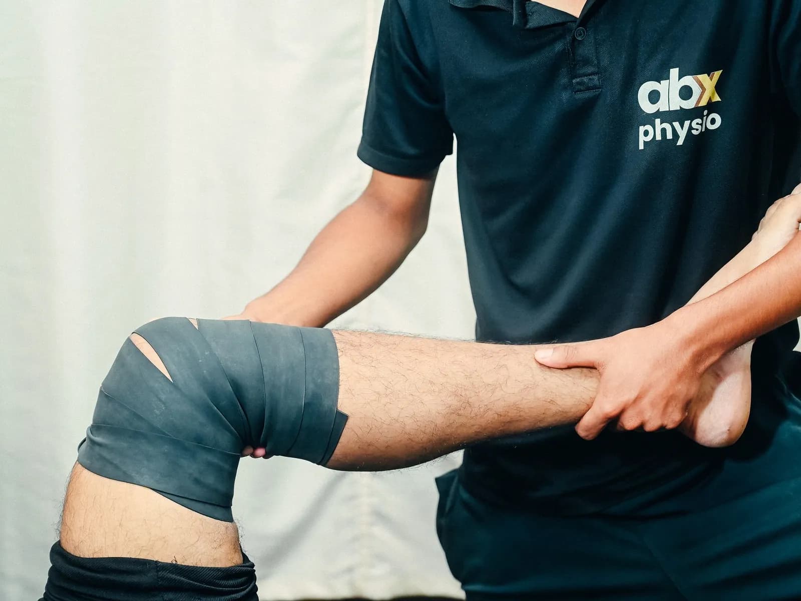 An ABX Physio therapist applying a compression floss band to a patient's knee